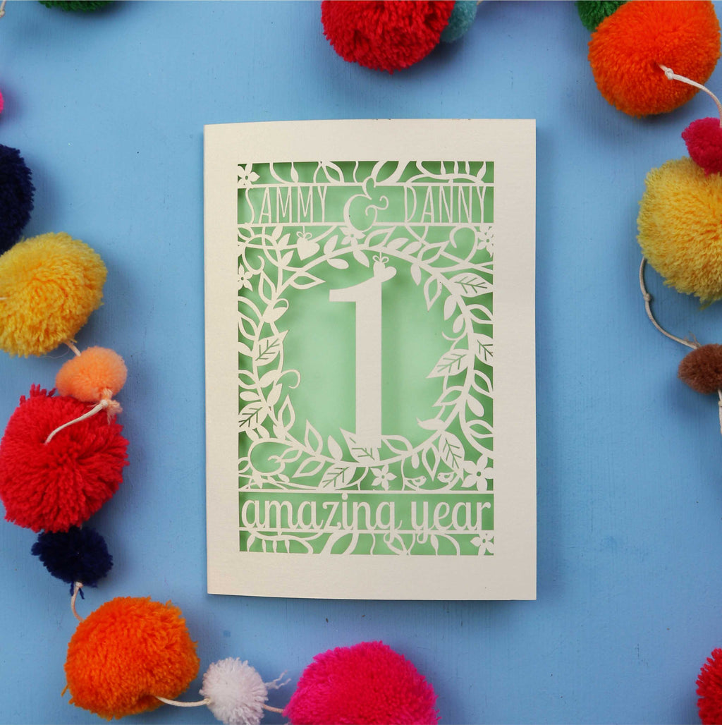 1st anniversary Card with cut-out design on a blue background with colourful pom-poms
