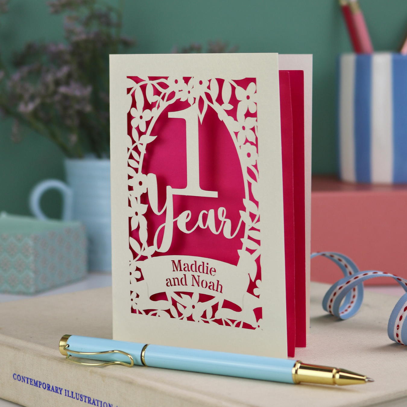 Card with '1 Year' design on a desk with a pen and decorative items.
