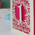 Card with a cut-out design of the number '1' and the text 'amazing year' on a pink background.
