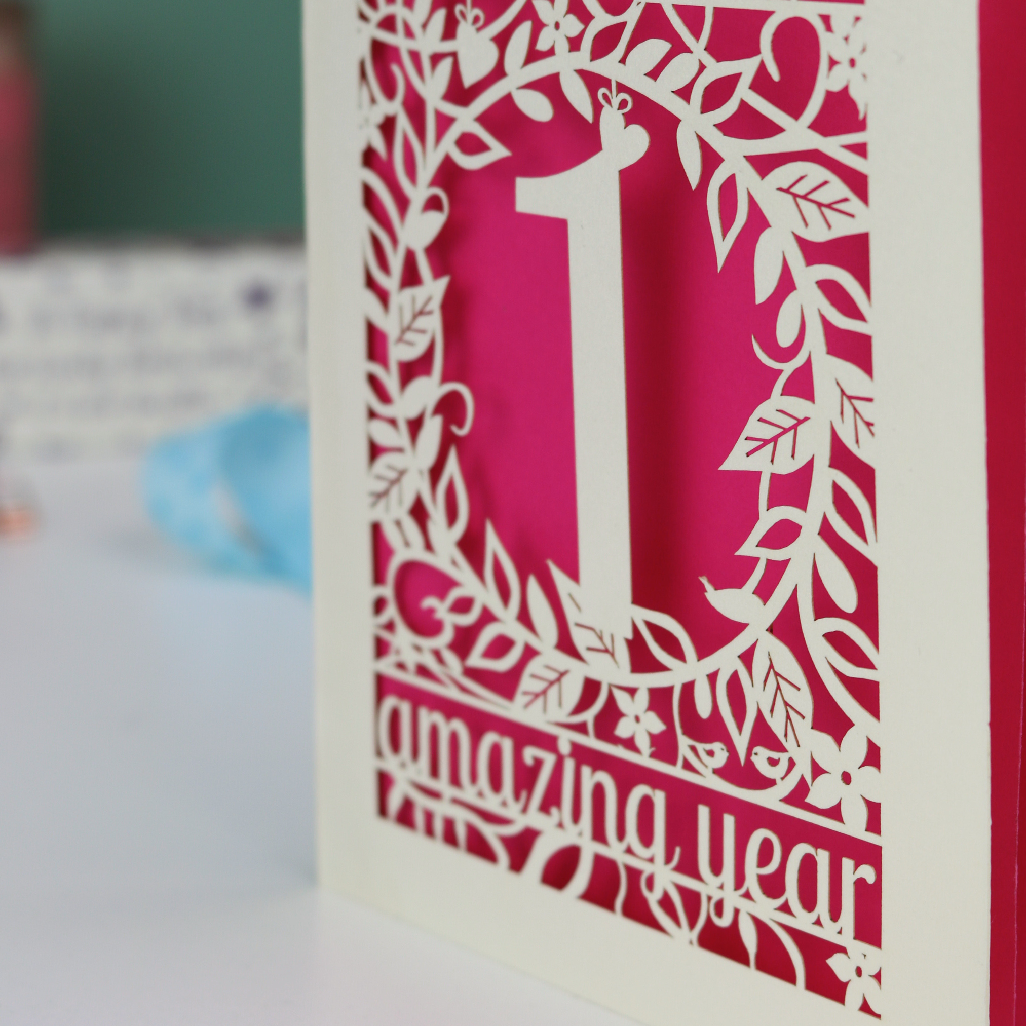 Card with a cut-out design of the number '1' and the text 'amazing year' on a pink background.