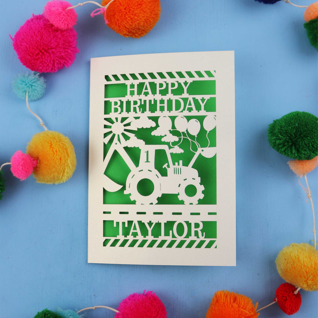 Birthday card with a tractor design and colourful pom-pom decorations on a blue background