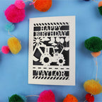 1st Birthday card with a tractor design and 'Happy Birthday Taylor' text on a blue background with colourful pom-poms.