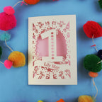 Laser-cut 1st birthday card with number '1' and name 'Lily Mae' on a blue background with colourful pom-poms.