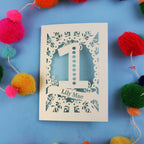 Baby's Birthday Card with '1' and 'Lily Mae' on a blue background with colourful pom-poms