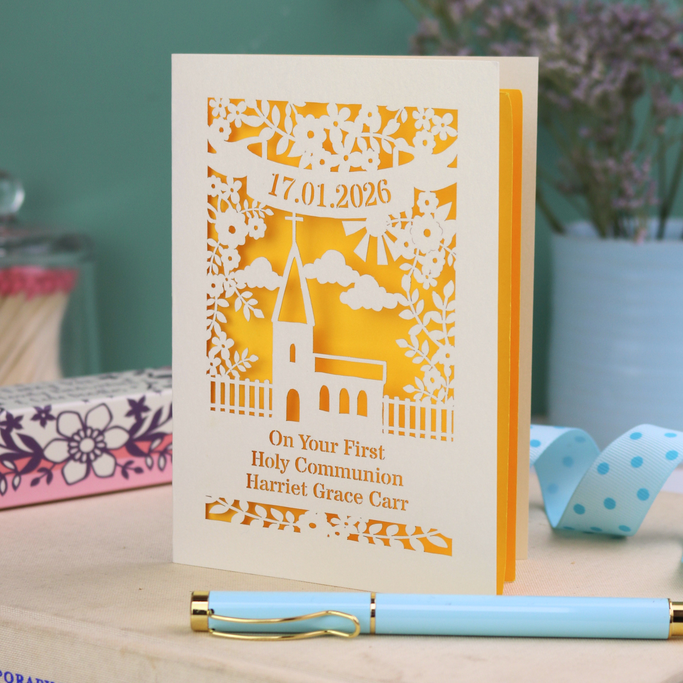 A cream and yellow laser cut 'On Your First Holy Communion' card with cut out church design, floral border, the date and name in cut out stencil font.