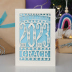 Pale blue and cream cards showing a cut out of the year and personalised with a name.