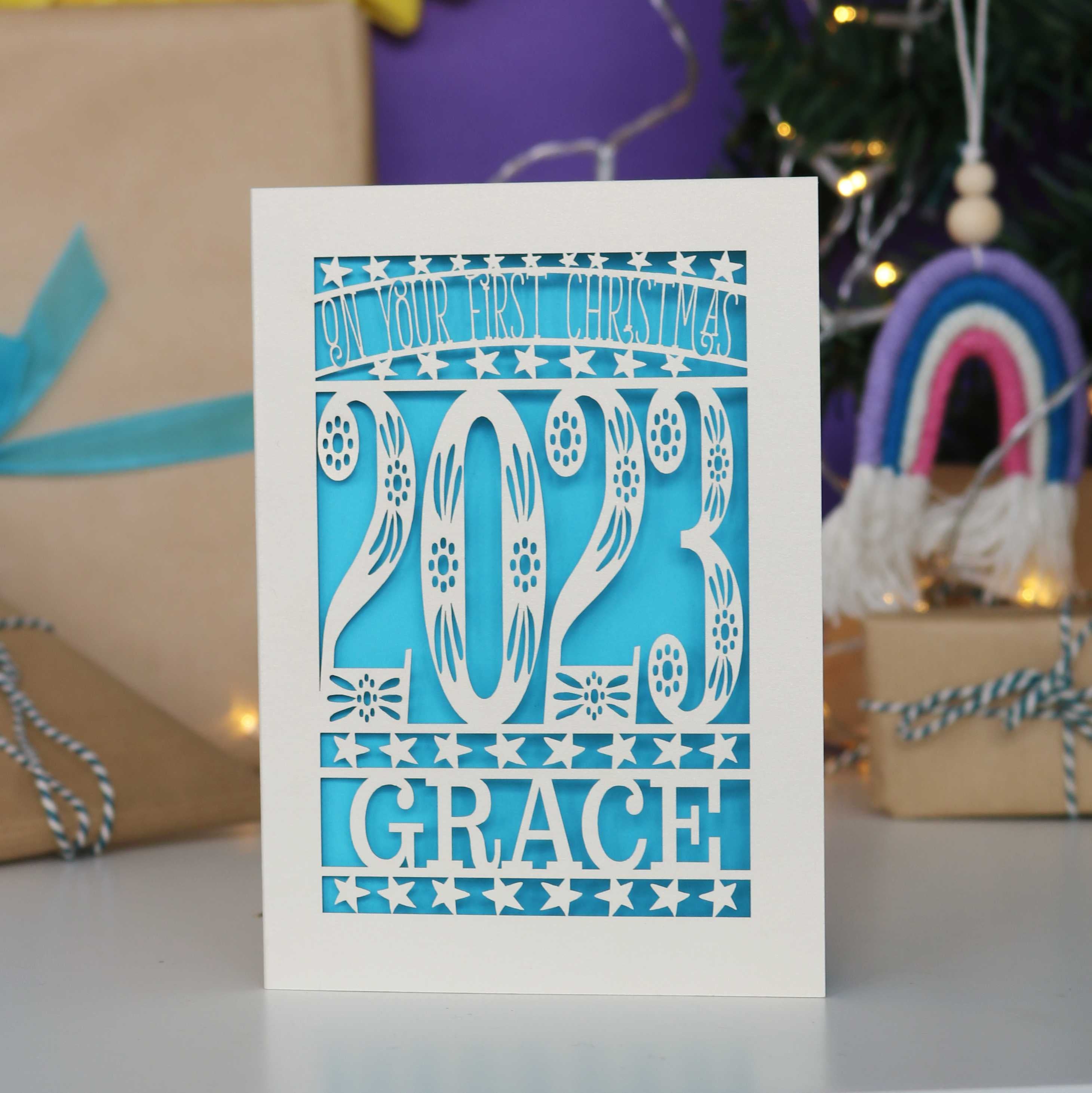 Laser cut baby's first Christmas card in cream with a blue background and personalised with the year and name