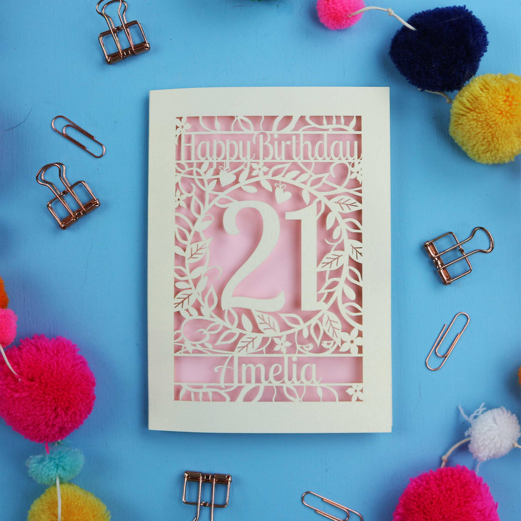 Personalized 21st birthday card with 'Happy Birthday Amelia' on a blue background with colourful pom-poms and paper clips.