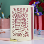 Laser-cut 21 birthday card with decorative elements on a table with stationery items.