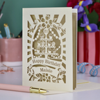 Laser-cut 21 birthday card with decorative elements on a table with stationery items.