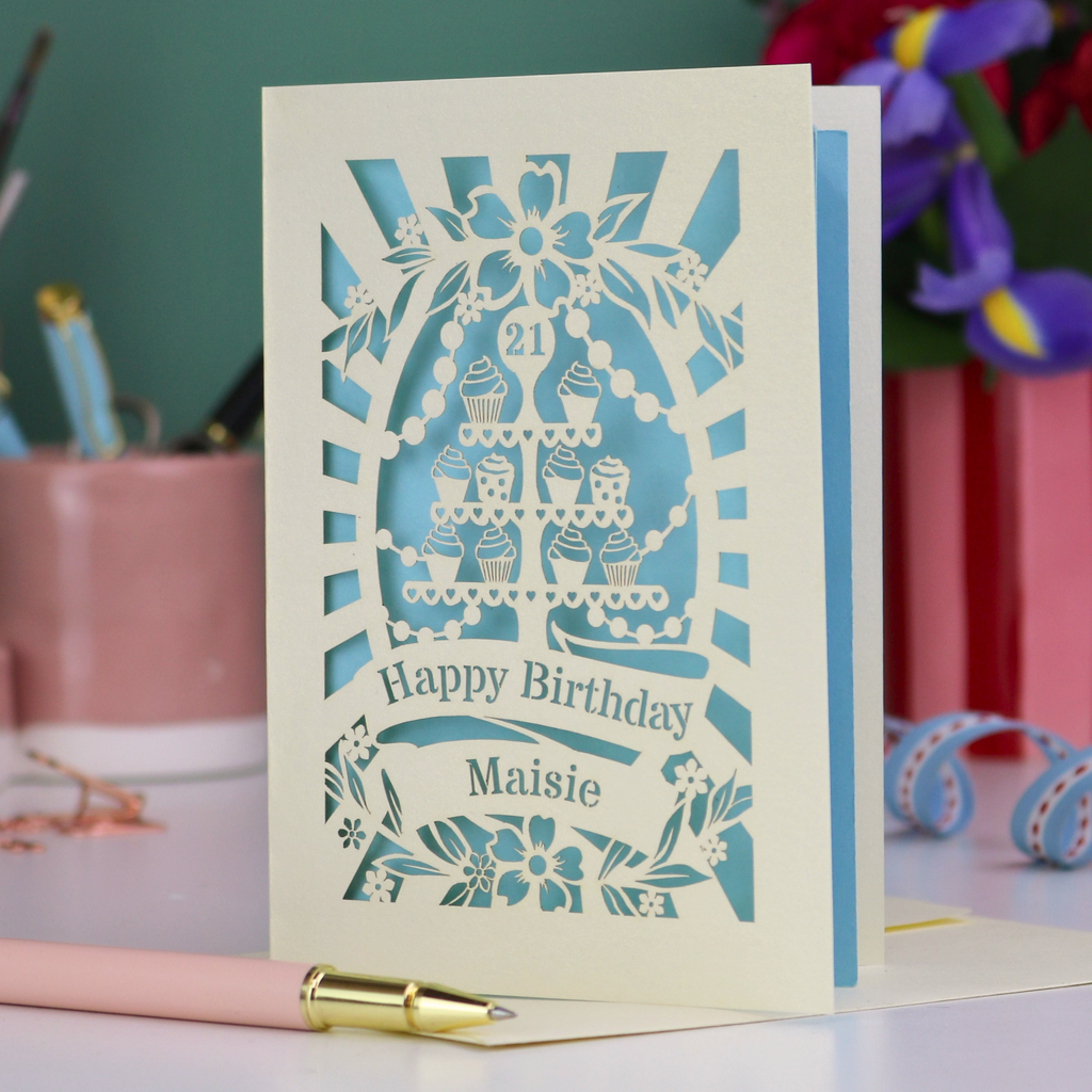 Laser-cut 21 birthday card with decorative elements on a table with stationery items.