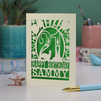 Cream and Green laser cut 21st birthday card with 'Happy Birthday Sammy' on a desk with stationery items.