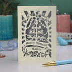 A laser cut personalised 21st Birthday card with decorative cupcake design and text on a desk with stationery items.
