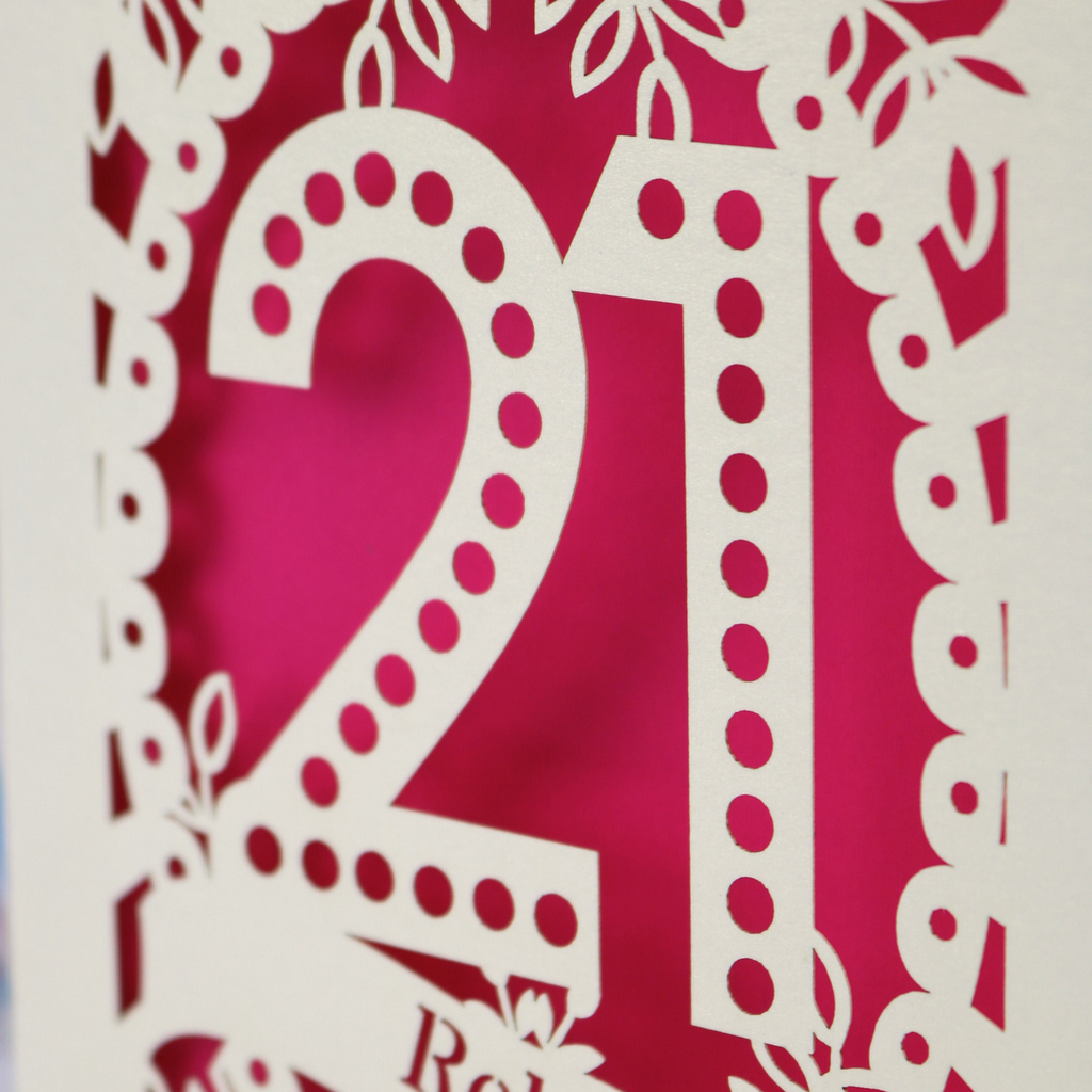 21st birthday card close up detail- a Laser cut number '21' with decorative elements on a shocking pink background