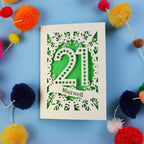 A 21st birthday Card with '21 Maxwell' design on a blue background with colourful pom-poms.
