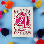 A 21st birthday Card with '21 Maxwell' design on a blue background with colourful pom-poms.