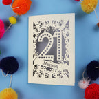 A 21st birthday Card with '21 Maxwell' design on a blue background with colourful pom-poms.