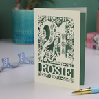 A cut out 21st birthday card, personalised with the name "Rosie", with the number 21 in the centre and woodland theme design, including tiny rabbits, a squirrel, owl, toadstools, leaves and flowers.