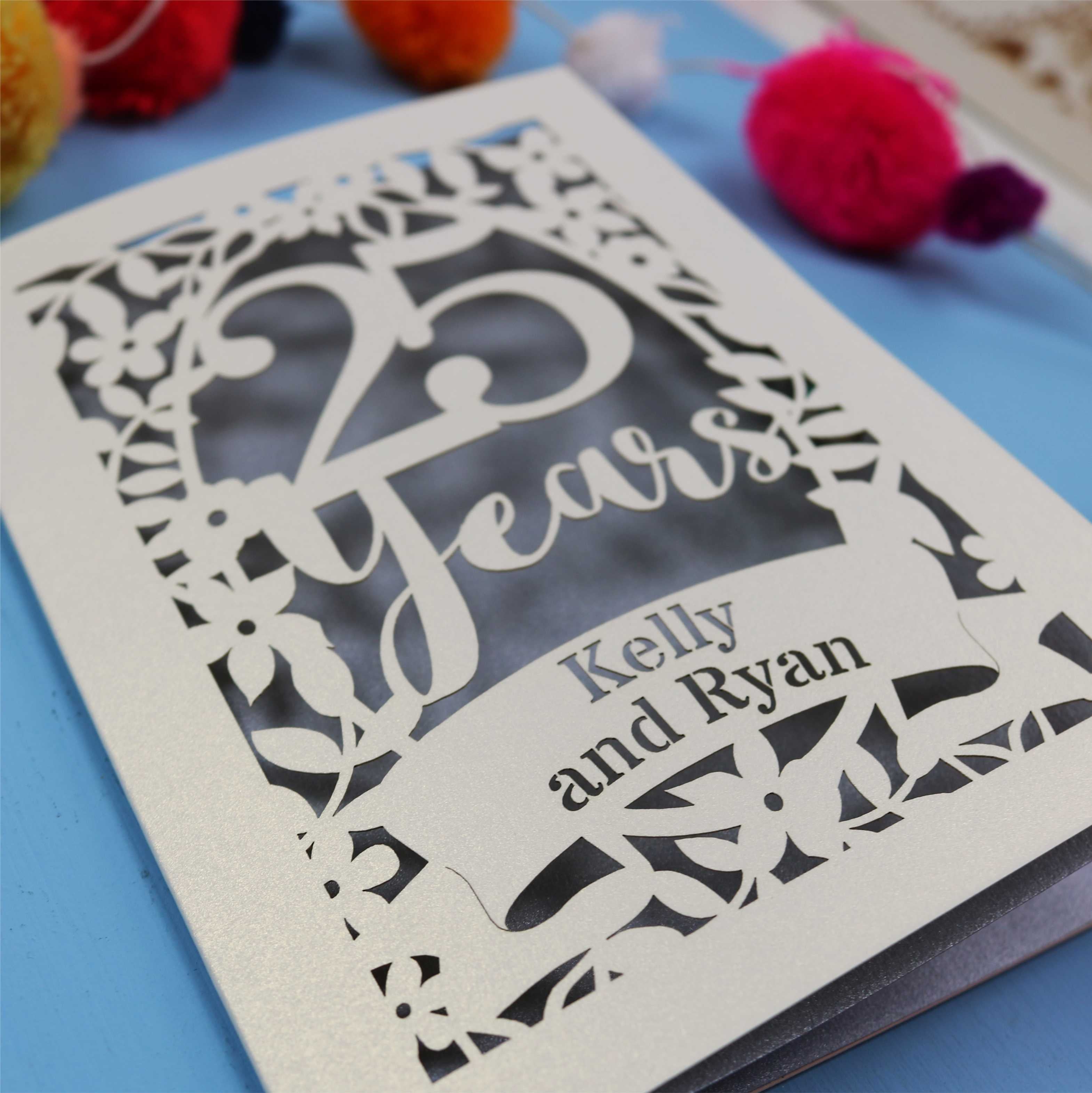 25th Anniversary Card with '25 Years' and 'Kelly and Ryan' text on a blue background with colourful pom-poms.