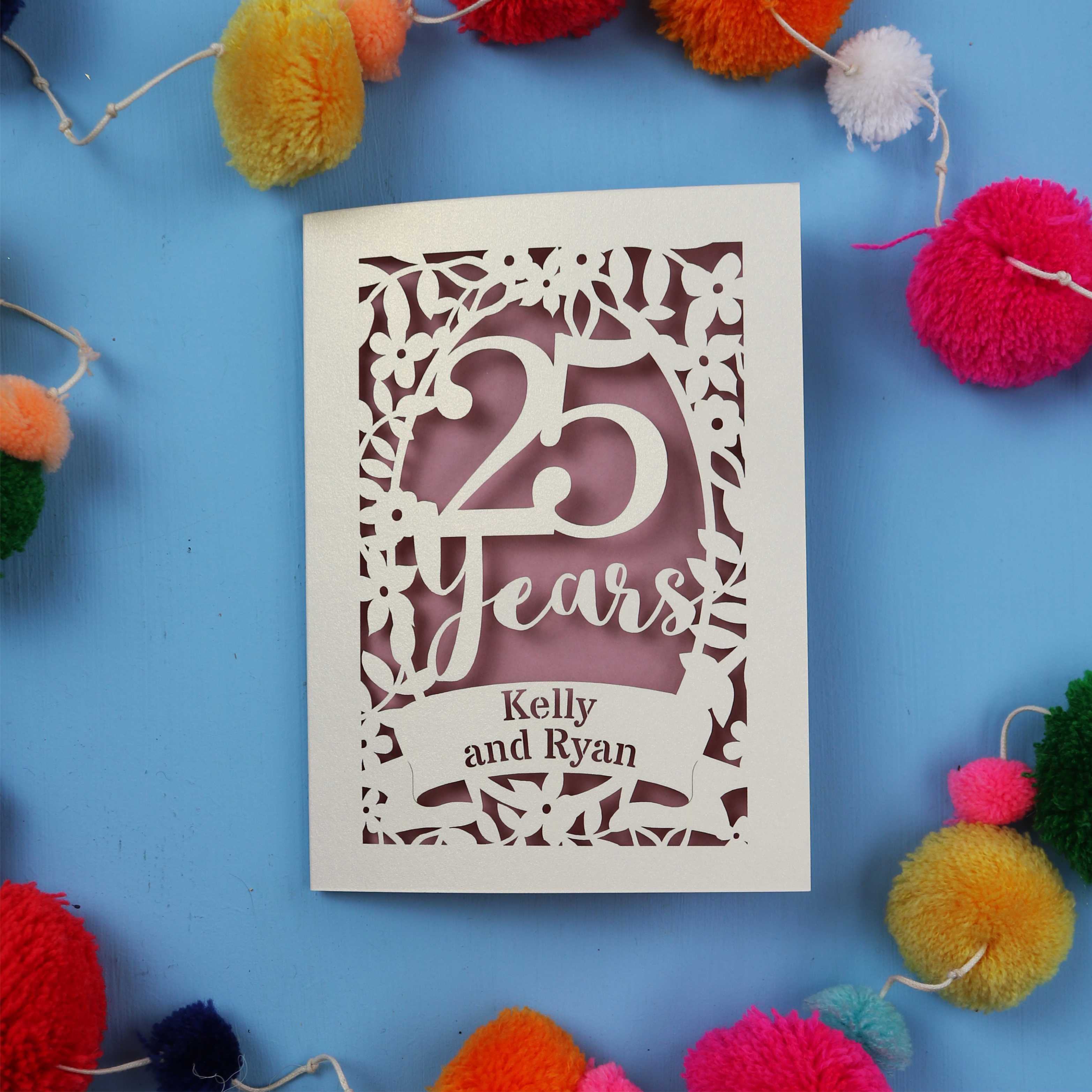 25th Anniversary Card with '25 Years' and 'Kelly and Ryan' text on a blue background with colourful pom-poms.