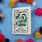 25th Anniversary Card with '25 Years' and 'Kelly and Ryan' text on a blue background with colourful pom-poms.