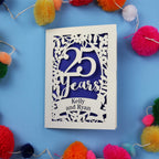 25th Anniversary Card with '25 Years' and 'Kelly and Ryan' text on a blue background with colourful pom-poms.