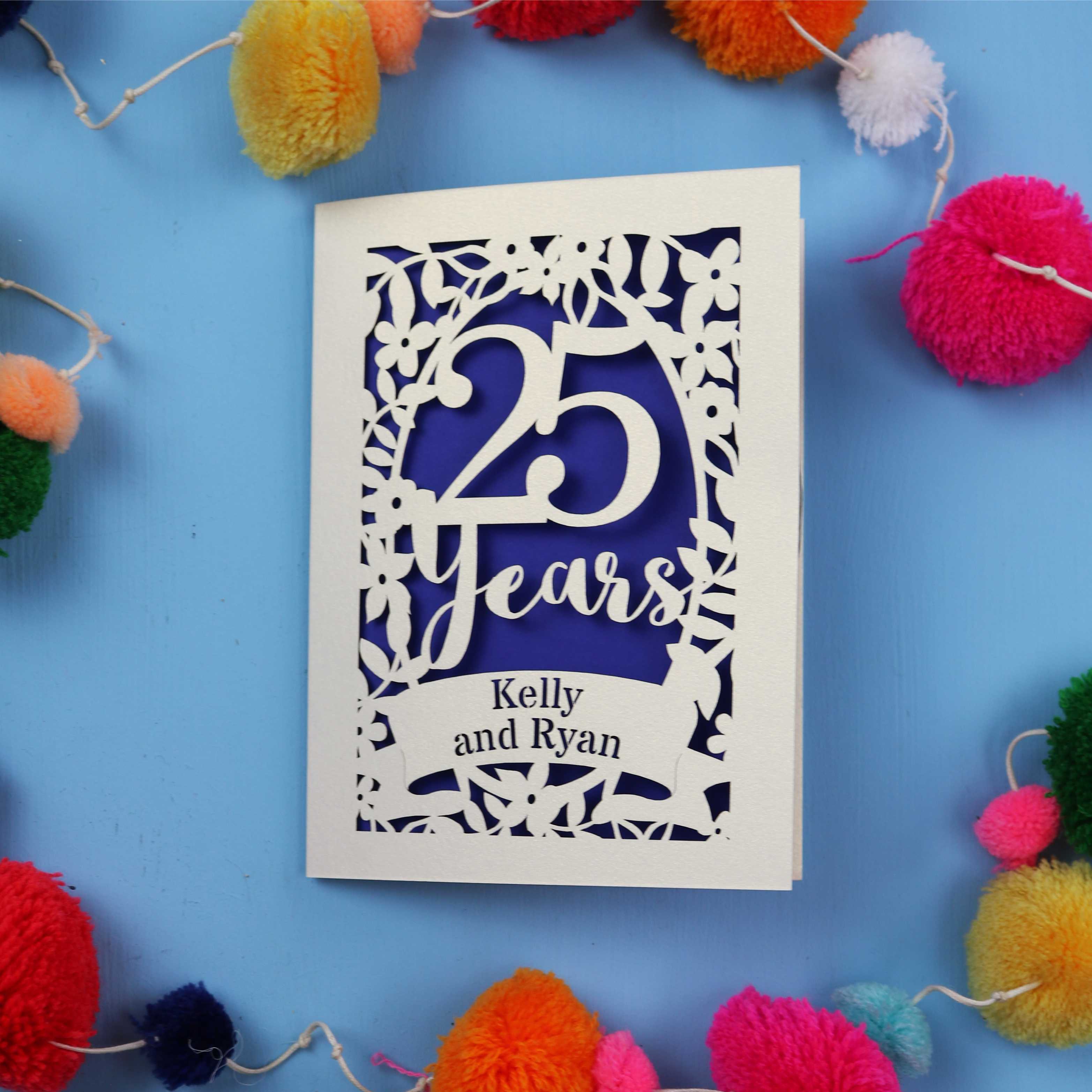 25th Anniversary Card with '25 Years' and 'Kelly and Ryan' text on a blue background with colourful pom-poms.