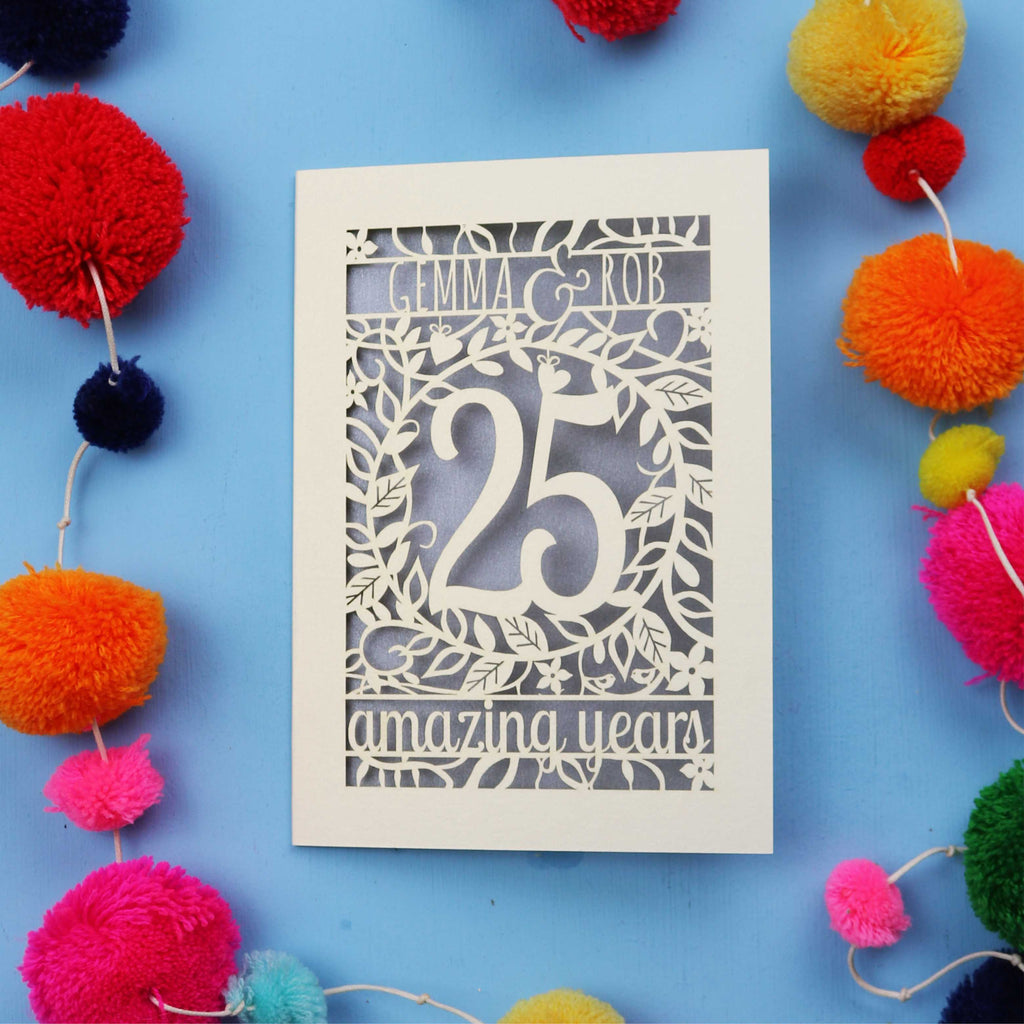 Silver wedding anniversary Card with '25 amazing years' text on a blue background with colourful pom-poms.