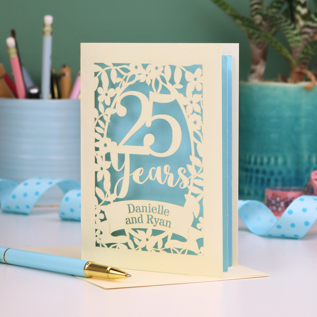 Silver anniversary Card with '25 Years' and 'Danielle and Ryan' on a desk with stationery items.