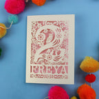 Laser cut 2nd birthday card with 'FREYA' design on a blue background with colourful pom-poms.