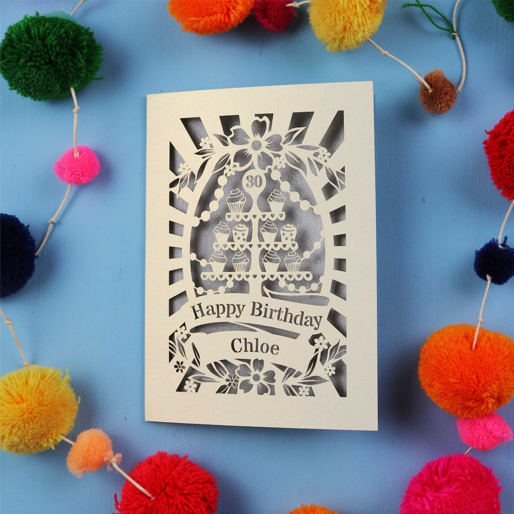 Laser-cut birthday card with colorful pom-poms on a blue background