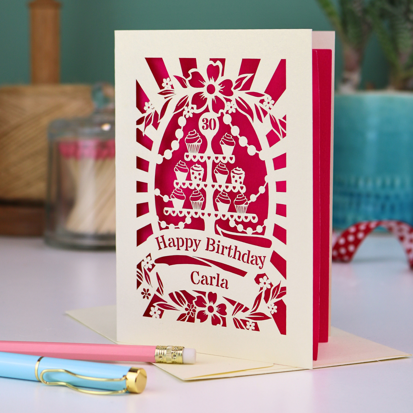Personalised 30th birthday card with decorative laser cut cupcake design and "Happy Birthday Name" on a table with stationery items.