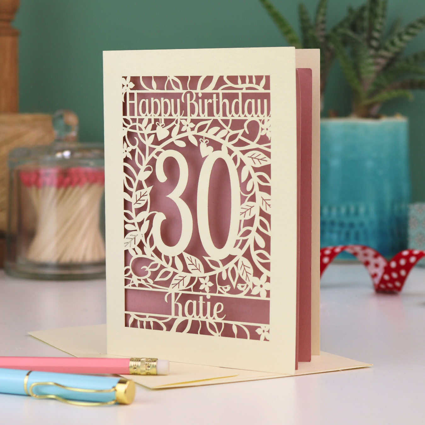 A laser cut 30th birthday card with floral cut out design, "Happy Birthday", 30, and personalised with a name. 