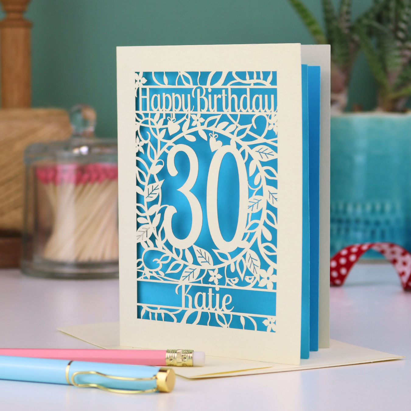A laser cut 30th birthday card with floral cut out design, "Happy Birthday", 30, and personalised with a name. 