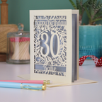 A laser cut 30th birthday card with floral cut out design, "Happy Birthday", 30, and personalised with a name. 