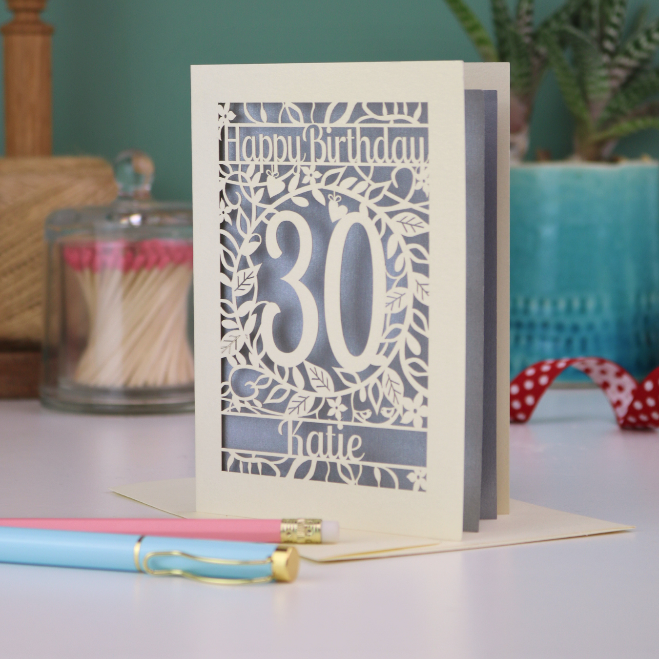 A laser cut 30th birthday card with floral cut out design, "Happy Birthday", 30, and personalised with a name. 