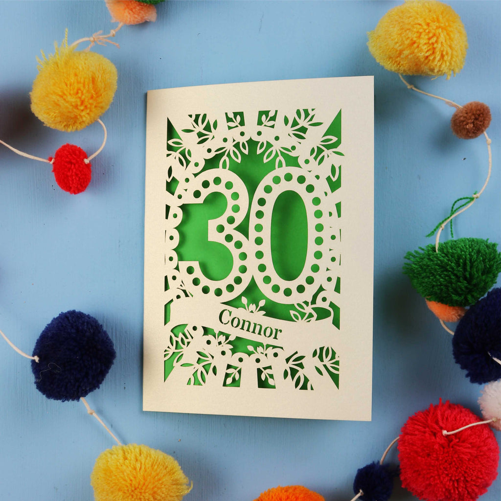 Laser cut 30th birthday card with '30 Connor' on a blue background with colourful pom-poms