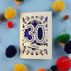 Laser cut 30th birthday card with '30 Connor' on a blue background with colourful pom-poms
