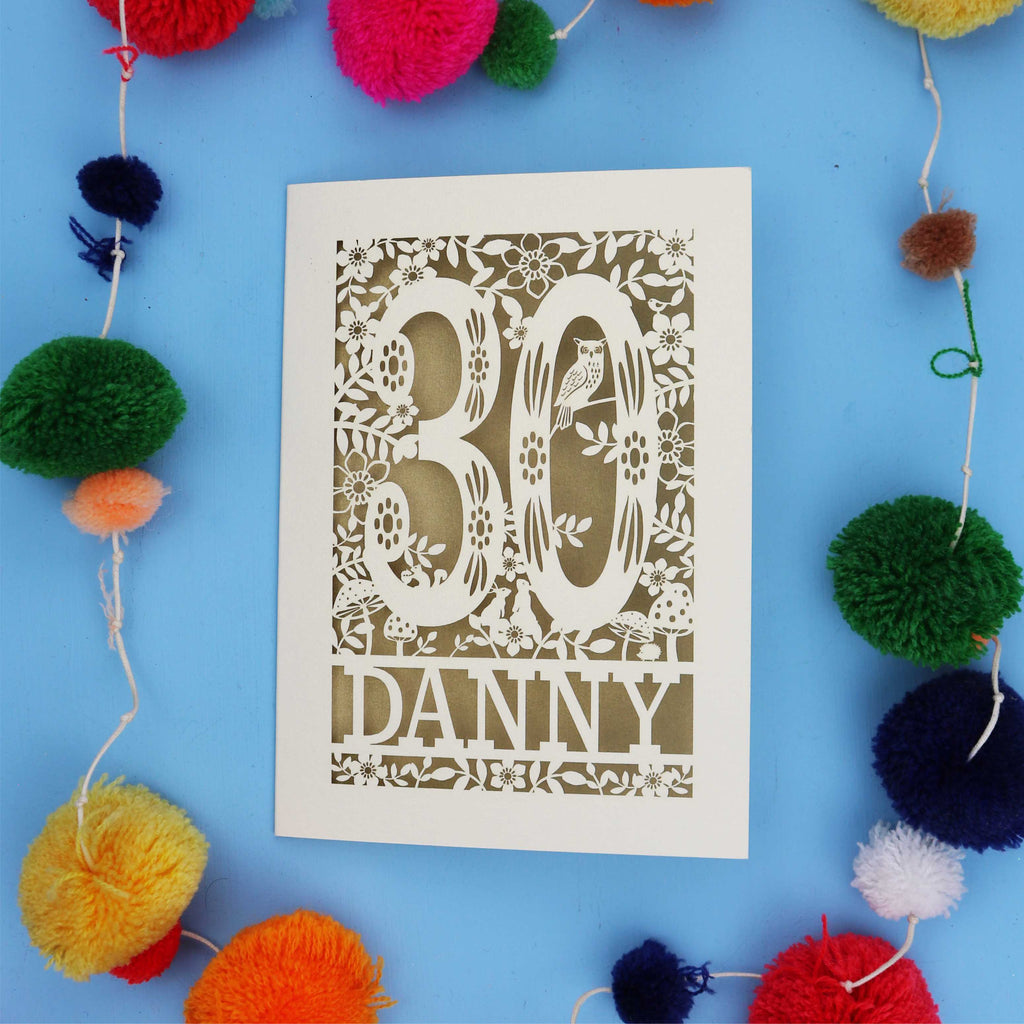 Decorative paper cut out 30th birthday card with '30 Danny' on a blue background with colourful pom-poms.