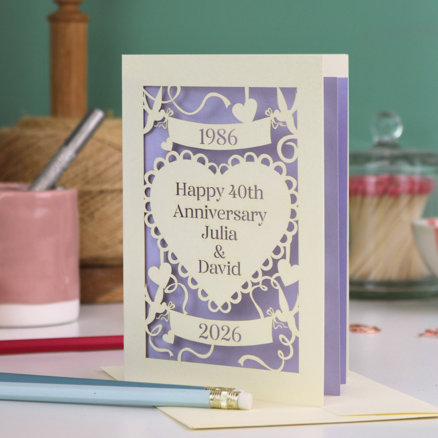 Anniversary card with personalized text on a table with stationery items.