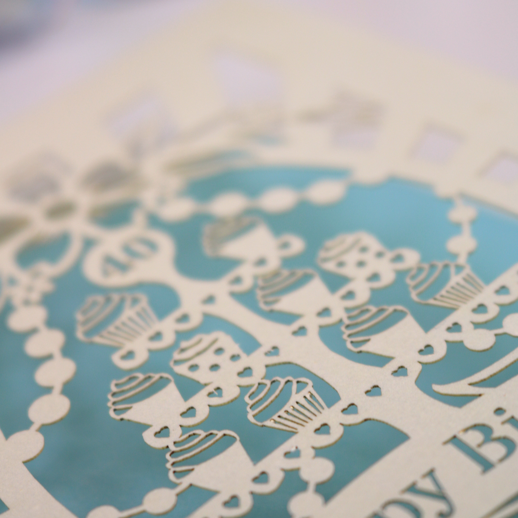 Decorative paper cutout with cupcake design on a blue background