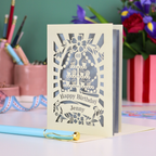 Personalized 40th birthday card with decorative cut-out cupcakes on a cake stand design on a desk with stationery items.