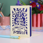 Personalized 40th birthday card with decorative cut-out cupcakes on a cake stand design on a desk with stationery items.