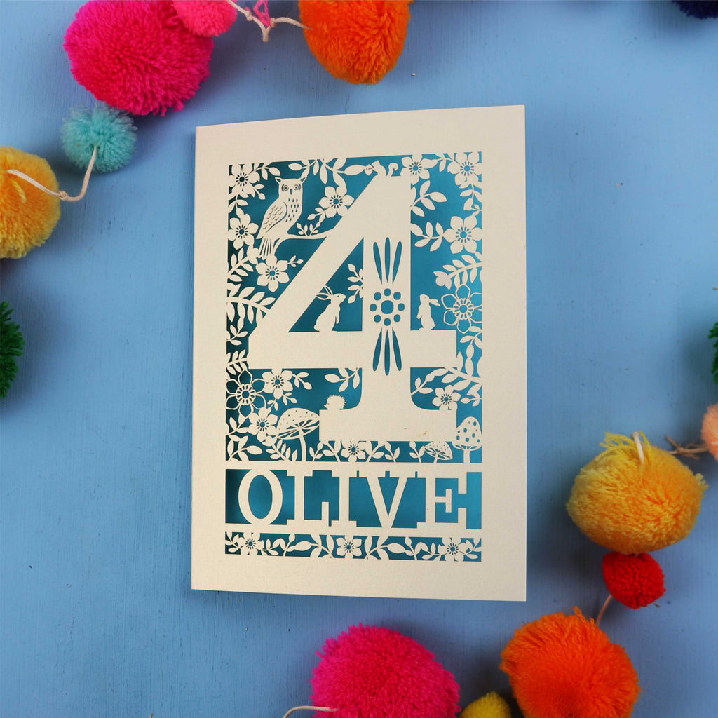 Personalised 4th birthday card with number '4' and 'OLIVE' text on a blue background with colourful pom-poms.
