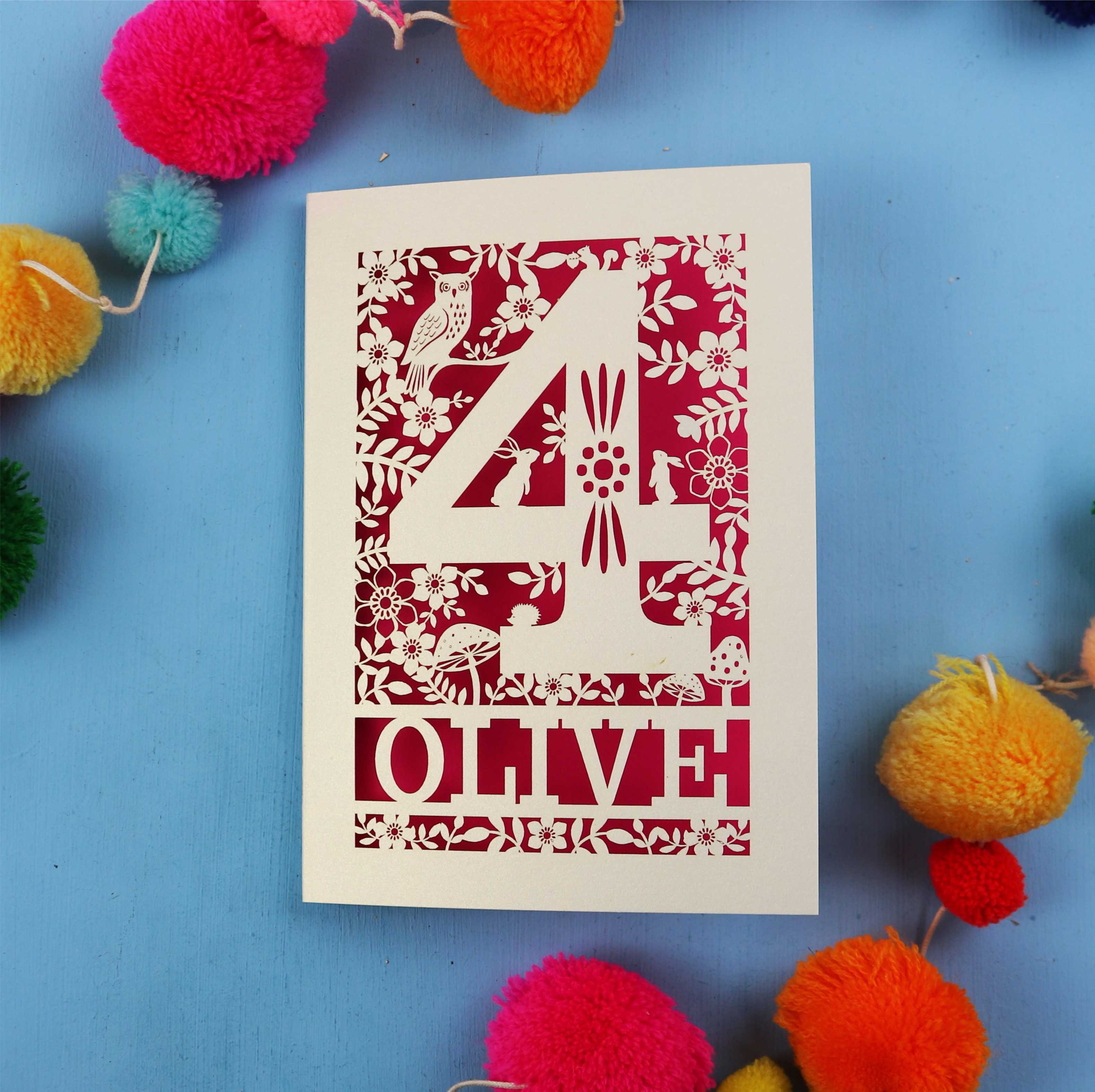 Woodland themed personalised 4th birthday card with number '4' and 'OLIVE' text on a blue background with colourful pom-poms.