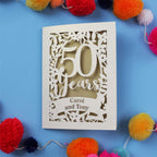 Golden Wedding anniversary Card with '50 Years Carol and Tony' on a blue background with colourful pom-poms.
