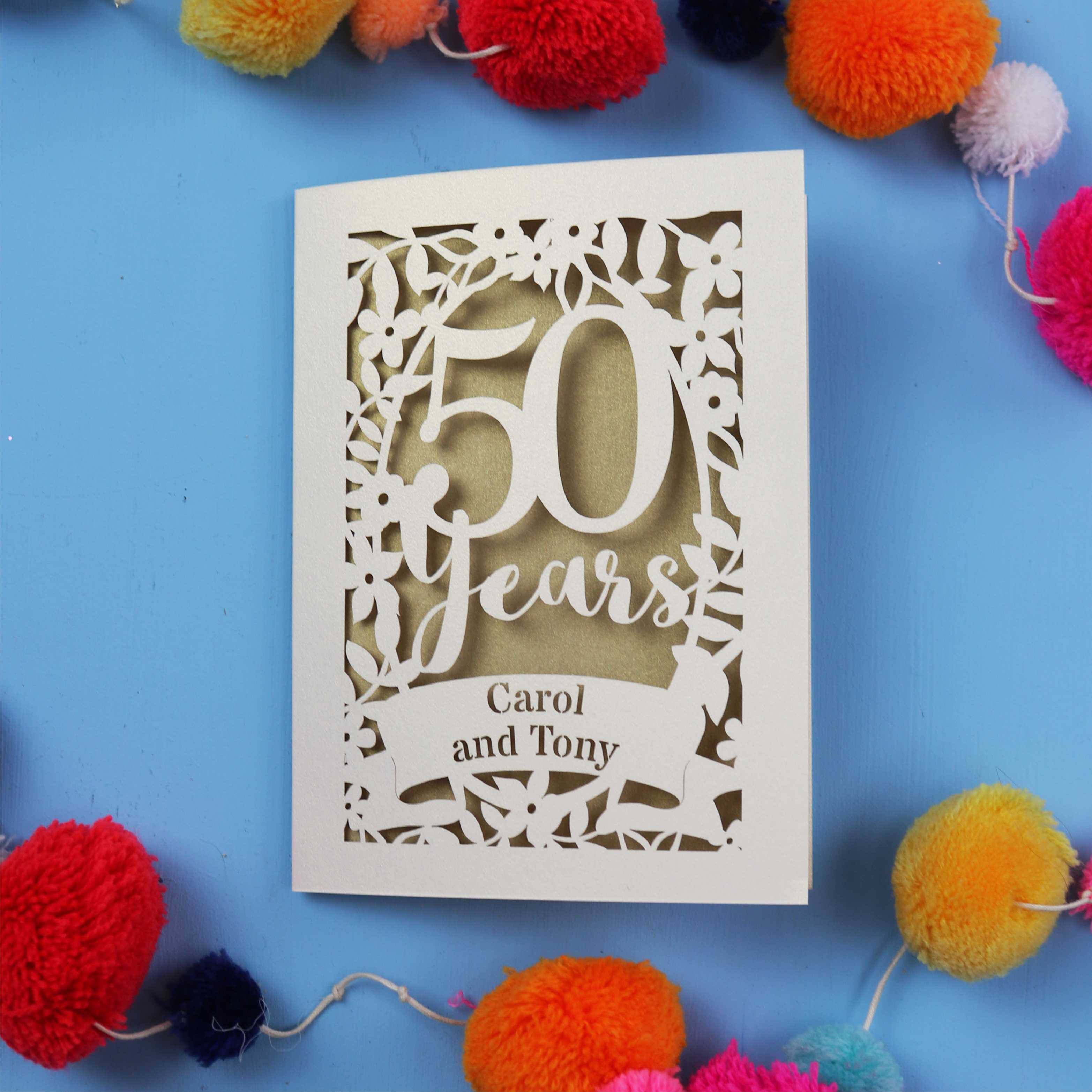 Golden Wedding anniversary Card with '50 Years Carol and Tony' on a blue background with colourful pom-poms.
