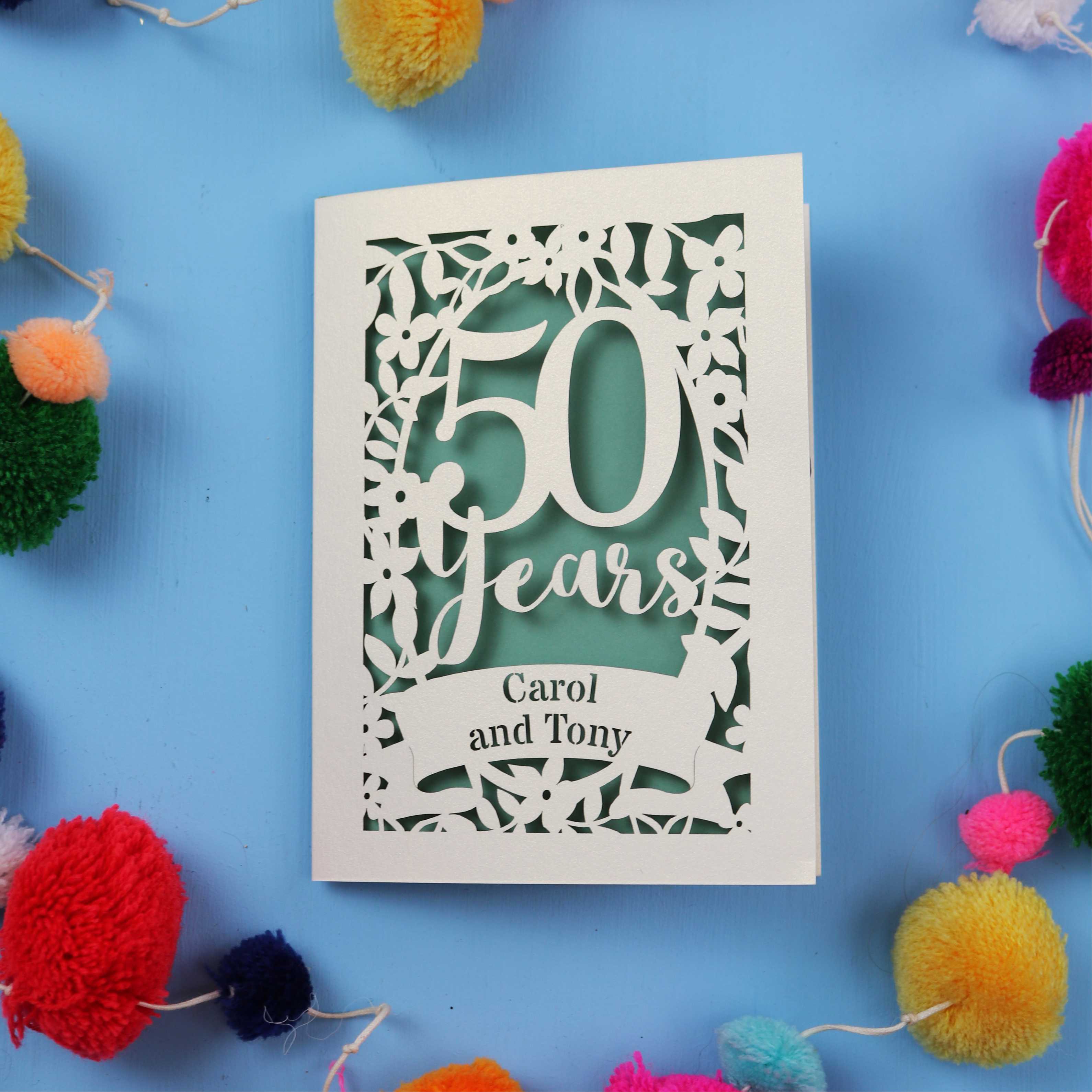 Golden anniversary Card with '50 Years Carol and Tony' on a blue background with colourful pom-poms.