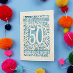 Golden wedding Anniversary Card with '50 amazing years' design on a blue background with colourful pom-poms.