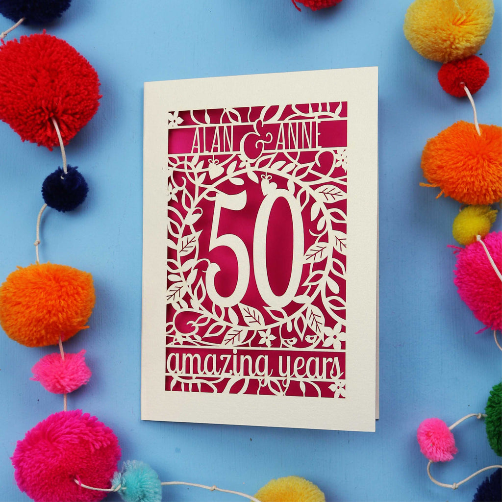 50th Anniversary Card with '50 amazing years' design on a blue background with colourful pom-poms.